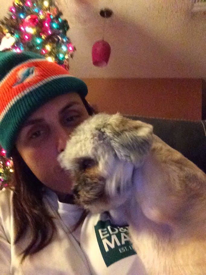 Paris giving Momma a kiss on the cheek by the Christmas tree, Momma in a Dolphins beanie