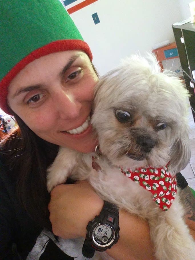 Momma in a green elf hat holding Paris cheek to cheek at Christmas