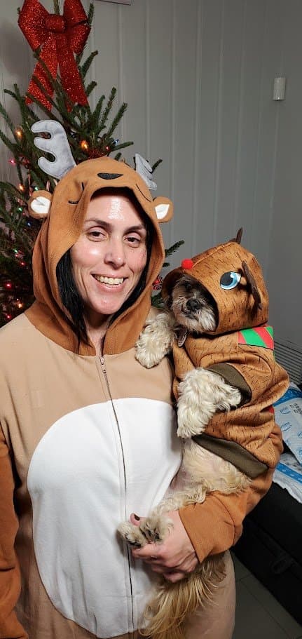 Momma in a reindeer onesie holding Paris in her matching reindeer costume in front of the Christmas tree