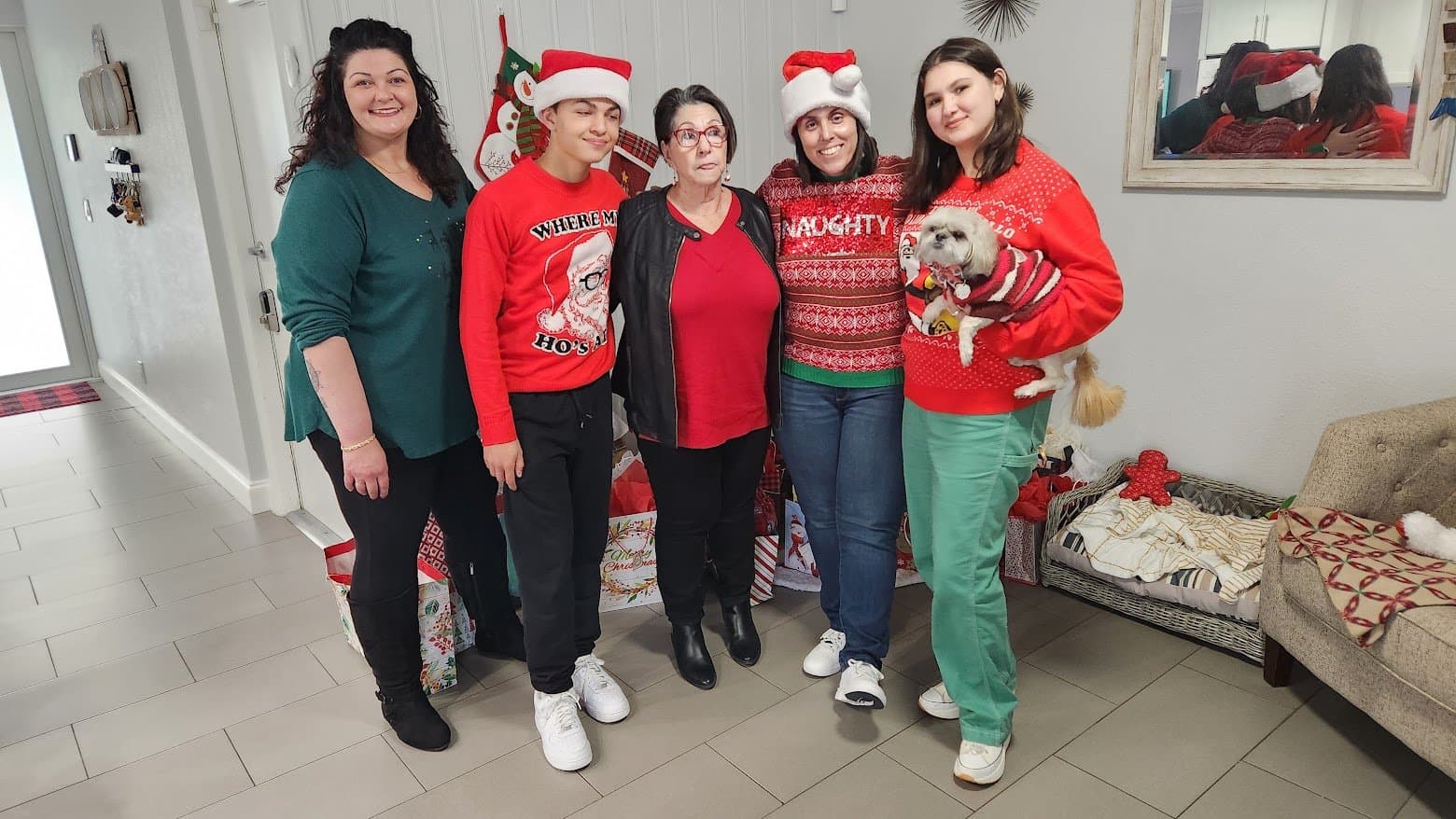 The whole family in Christmas sweaters gathered together, Paris held in someone's arms
