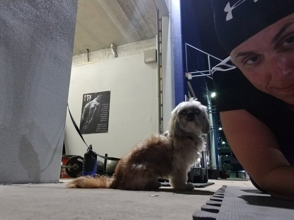 Momma down on the gym floor in a beanie with Paris sitting beside her near the weights