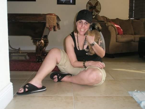 Momma sitting on the floor holding puppy Paris, smiling.