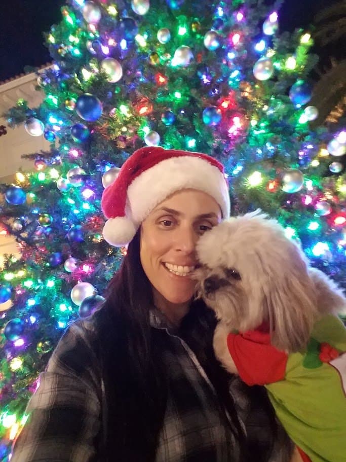 Momma and Paris in front of a big lit Christmas tree, Paris kissing her cheek.